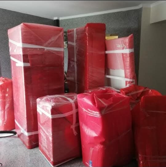 Kırılgan eşyaların kırmızı koruma örtüsüyle sarılarak paketlenmesi